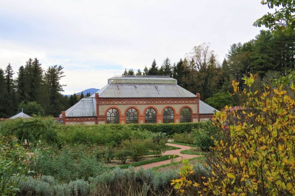 The famous conservatory building at the Biltmore Estate with large, rounded windows on its beige front with orange and red trim.