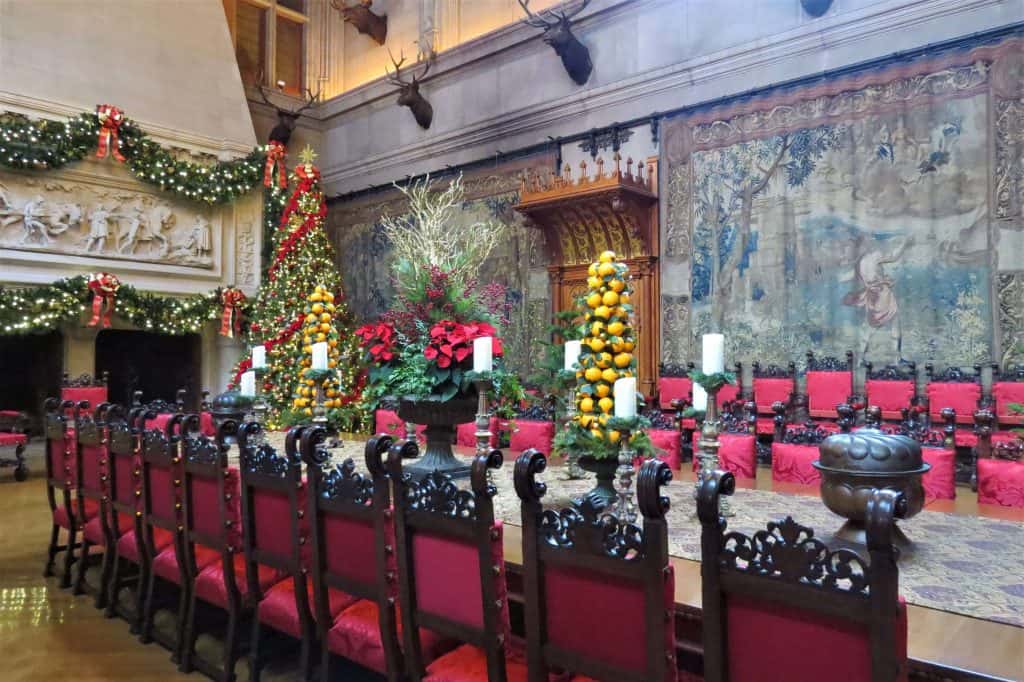 The large dining table lined with ornate chairs lined in red.