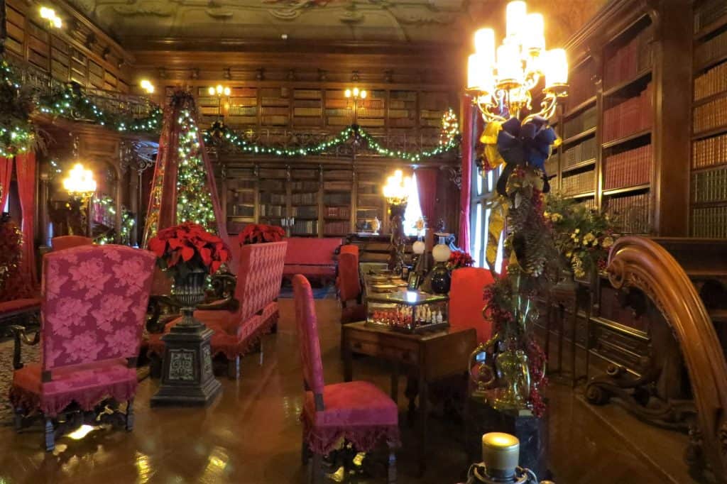 The ornate bookshelves and luxurious red chairs in the library of the Biltmore Estate.