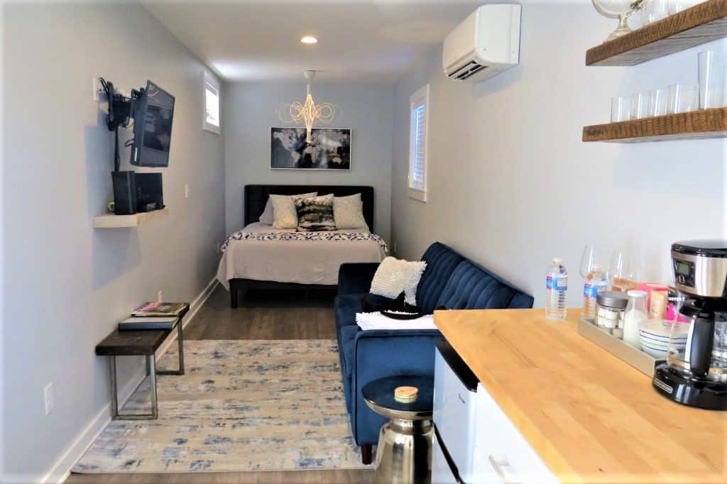 Interior of storage container with queen bed, blue couch and small kitchen in a row down the rectangular interior.