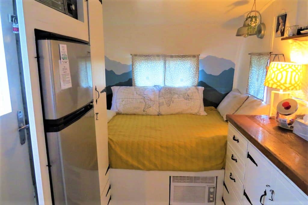 Interior of vintage trailer is very tight with refrigerator, dresser, and bed.