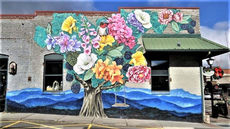 Street mural of a tree with blooming flowers and a swing in downtown West Jefferson.