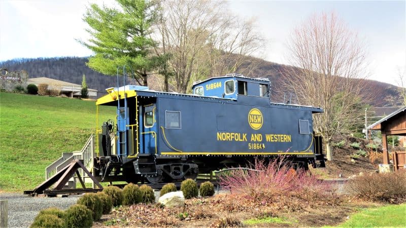 Old blue train car with Norfolk and Western in yellow lettering in downtown West Jefferson