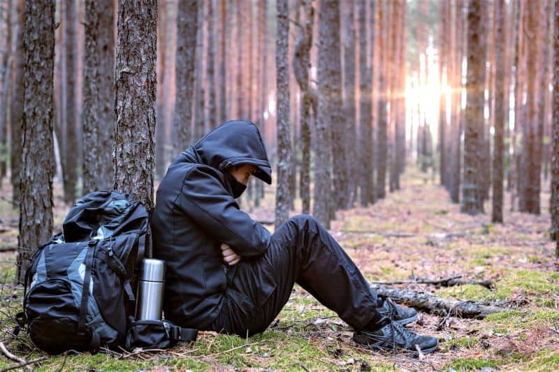 Hiker in the woods cold and unhappy.