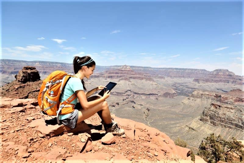 Woman sitting on rim at Grand Canyon with app.