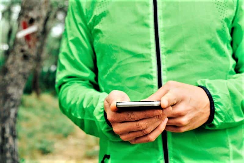 Day hiker in woods checking phone.
