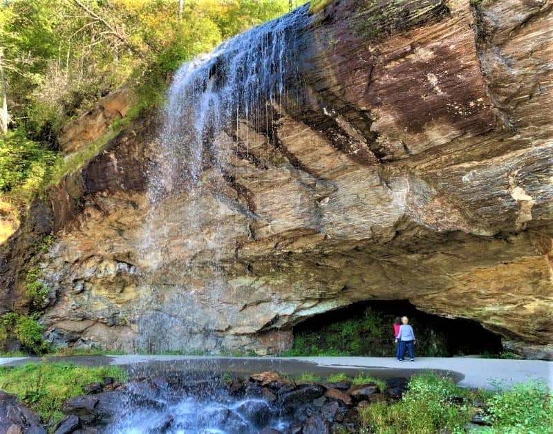 Two people standing under Looking Glass Falls.