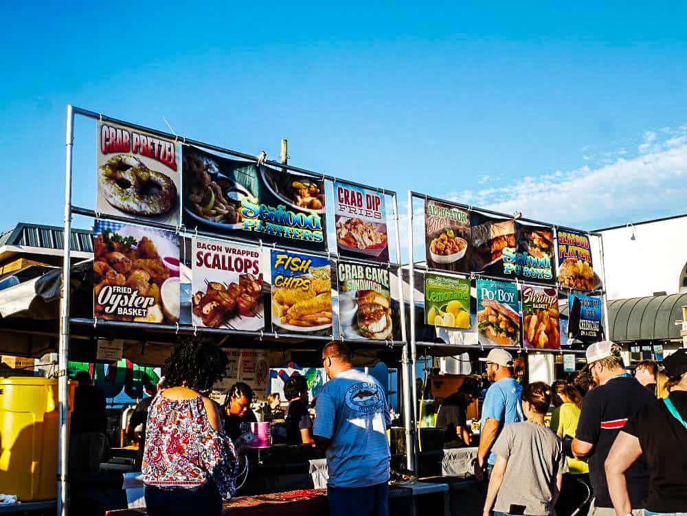 A food vendor selling a variety of different shrimp and fish dishes.