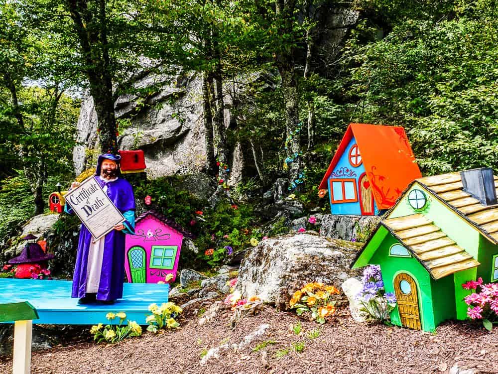 Munchkin Land at Oz with Munchkin holding certificate of death for wicked witch.