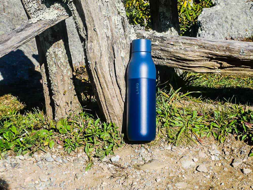 Navy blue LARQ PureVis water bottle leaning against fence on the Blue Ridge Parkway