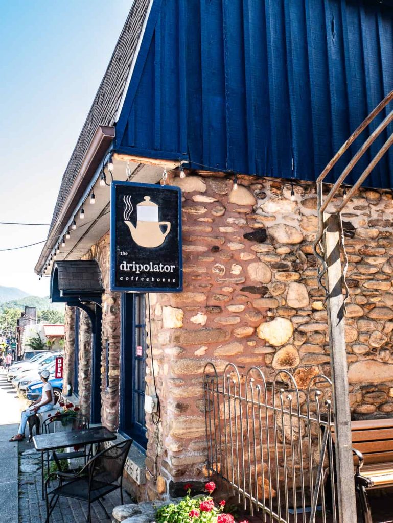View of stone building that is home to Dripolator coffee with blue roof and blue trim on door and windows. 