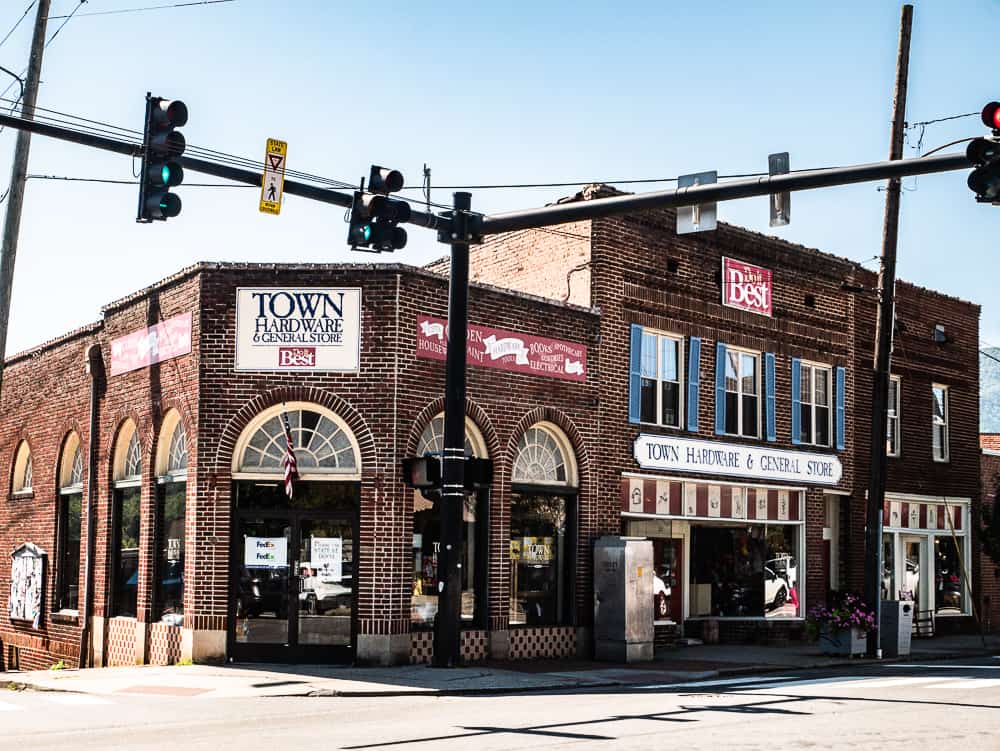 Three brick buildings on a street corner with traffic lights that make up Town Hardware and General Store. 