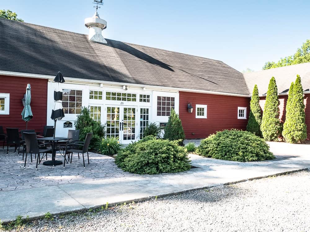Red building with large white French doors and seating outside. 